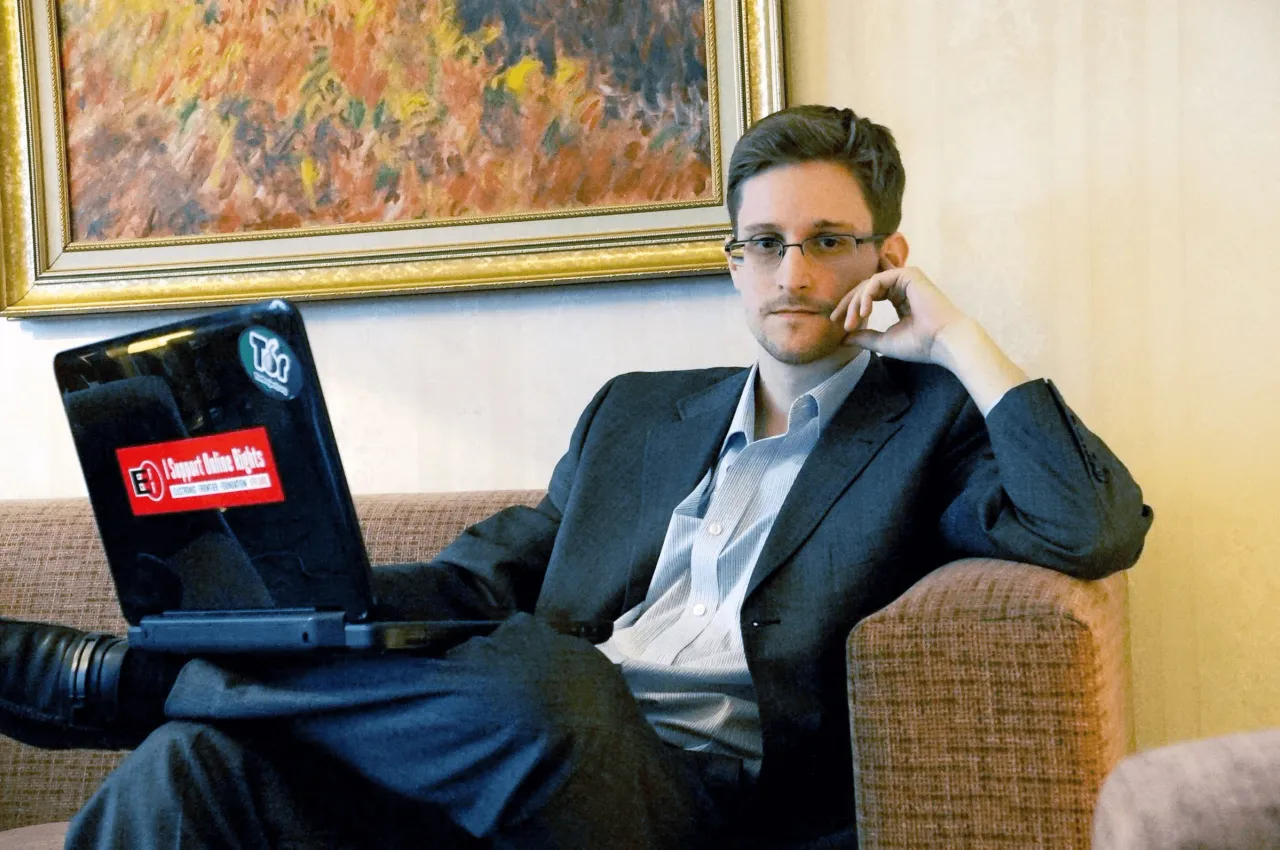 Edward Snowden sitting with his laptop. A symbolic image representing privacy, surveillance, and whistleblowing, used in the blog on zibonthinks.framer.ai by Khalid Hasan Zibon (খালিদ হাসান জীবন এর ভাবনা, ব্লগ)। এডওয়ার্ড স্নোডেন ল্যাপটপ নিয়ে বসে আছেন। প্রাইভেসি, নজরদারি এবং হুইসেলব্লোয়ার ভাবনার প্রতীক হিসেবে ব্যবহৃত একটি চিত্র, zibonthinks.framer.ai ব্লগে খালিদ হাসান জীবন এর লেখায়।